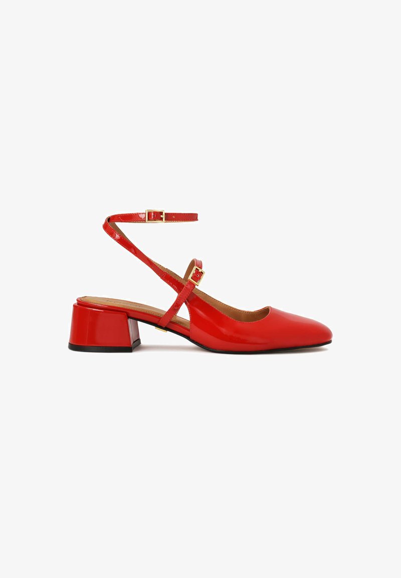 Chaussure slingback en cuir verni rouge avec un bout pointu et un petit talon carré. Elle possède une sangle ajustable à la cheville avec une boucle en or.