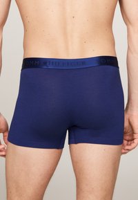 Temno modre bokserice iz mehkega materiala z oprijetim krojem in pasom z vgraviranim napisom "TOMMY HILFIGER" v usklajeni barvi.
