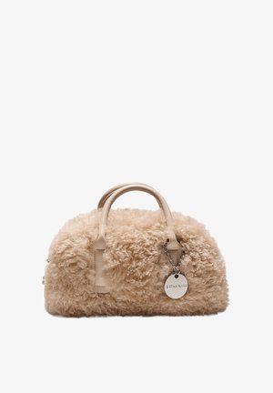 Sac à main beige en fausse fourrure pelucheuse avec des poignées en cuir arrondies et une étiquette circulaire en métal de la marque attachée par une chaîne.