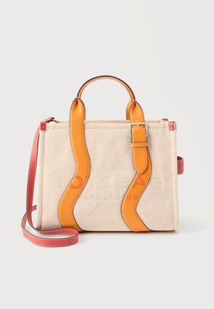 Sac fourre-tout en toile beige avec poignées incurvées en cuir marron clair, bandoulière rouge réglable et texte discrètement embossé à l'avant.