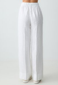 Pantalons larges en lin blanc avec taille élastique. Présente une coupe décontractée, une texture subtile et une finition propre des ourlets.