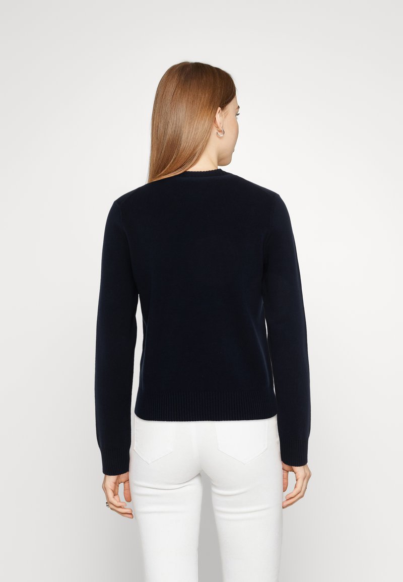 Maglione lavorato a maglia blu navy con maniche lunghe e scollo rotondo, con orlo e polsini a coste, mostrato dal retro.