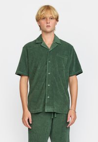 Korte mouwen, button-up shirt in donkergroen terrycloth, met een kraag, voorzak en een relaxte pasvorm. Zachte textuur met een subtiele glans.