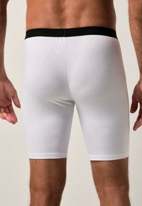 Boxer briefs blancos hechos de un material suave con una cinturilla negra que lleva el texto "JP1880". Diseñados para un ajuste ceñido, resaltando la silueta.