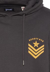 Szara bluza z kapturem wykonana z bawełnianej mieszanki, z troczkiem, żółtą grafiką gwiazdy i chevronu na piersi oraz miękkim, teksturowanym wykończeniem.