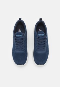 Scarpe da ginnastica blu navy con tomaia in tessuto a maglia, punta tonda e suola in gomma bianca. Presentano sei fori per i lacci e una linguetta imbottita. Logo del marchio sul lato.
