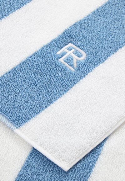 Asciugamano a righe blu e bianche con una trama morbida, caratterizzato da un logo bianco ricamato. Le righe alternano larghezze diverse, offrendo un design semplice.