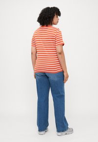 Orange striped t-shirt with short sleeves, paired with blue jeans. T-shirt has a round neckline and a relaxed fit. Smooth cotton texture.