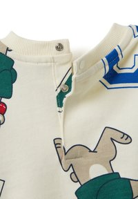 Crème kleurige trui met een geribbelde halslijn, voorzien van kleurrijke cartoonfiguren prints en drukknoopjes op de kraag.