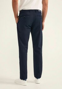 Chinos blu navy con taglio dritto, realizzati in tessuto misto cotone, con due tasche posteriori con chiusura a bottone e una texture morbida e liscia.