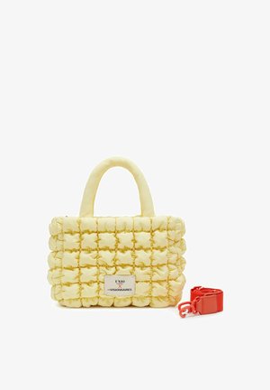 Borsa trapuntata giallo chiaro con manici superiori e tracolla arancione brillante rimovibile, con una piccola etichetta bianca del marchio sul davanti.