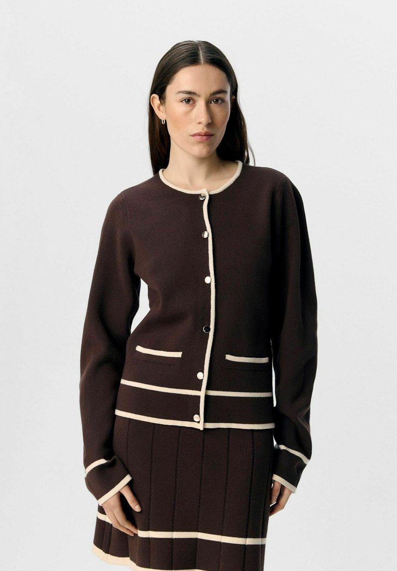 Brun cardigan med creme-stribede detaljer, med rund halsudskæring, knaplukning, lange ærmer og to frontlommer. Blød tekstur.