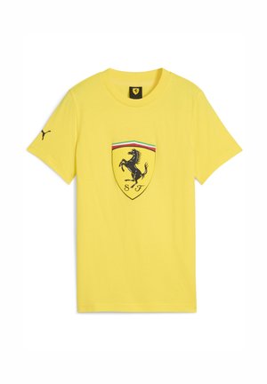 Geltona marškinėliai su Ferrari logotipu centre, juoda šuoliuojančia žirgu ir spalvotomis juostomis virš emblemos.