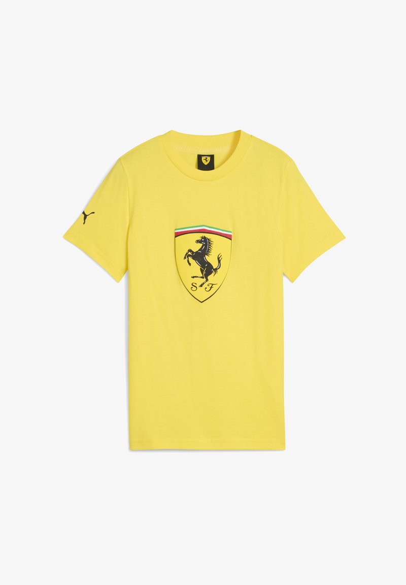 Geltona marškinėliai su Ferrari logotipu centre, juoda šuoliuojančia žirgu ir spalvotomis juostomis virš emblemos.