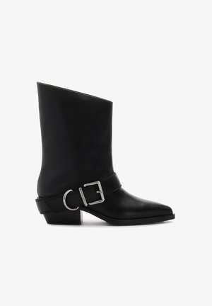 Czarne skórzane botki za kostkę z wydłużonym noskiem, srebrną klamerką oraz niskim, blokowym obcasem. Gładka tekstura z minimalnymi detalami.