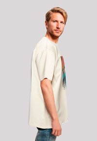 Crèmekleurig katoenen T-shirt met een kleurrijk grafisch ontwerp op de voorkant, korte mouwen en een casual pasvorm.