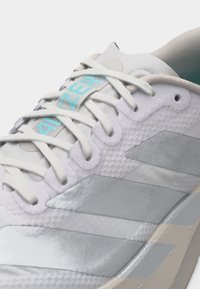 Λευκό και ανοιχτό γκρι αθλητικό παπούτσι με υφασμάτινο επάνω μέρος, λευκά κορδόνια και μπλε κείμενο "ADIZERO" στη γλώσσα.