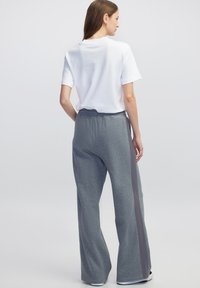 Grijze joggingbroek met een losse pasvorm, met een contrasterende zijstreep. Gepaard met een eenvoudige witte t-shirt met korte mouwen, gemaakt van zachte katoen.