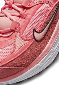 Urheilukengät vaaleanpunaisissa sävyissä, joissa on yhdistelmä verkko- ja mokkatekstuureja, voimakkaalla mustalla Swoosh-logoilla ja monimutkaisilla ompeluyksityiskohdilla.