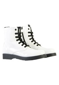 Botas de tobillo de charol blanco con acentos negros, que cuentan con cordones y una cremallera lateral, y una suela de goma negra texturizada.