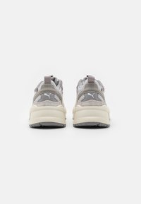 Valkoiset ja beige tennarit, joissa on verkko- ja mokkanahkainen materiaali, paksu pehmustettu pohja, pehmustettu nilkkapanta ja voimakas RS-X-brändäys kannassa.