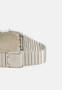 Montre-bracelet en acier inoxydable avec surface brossée, boîtier octagonal et bracelet maillons doté d'une fermeture sécurisée gravée "CASIO".