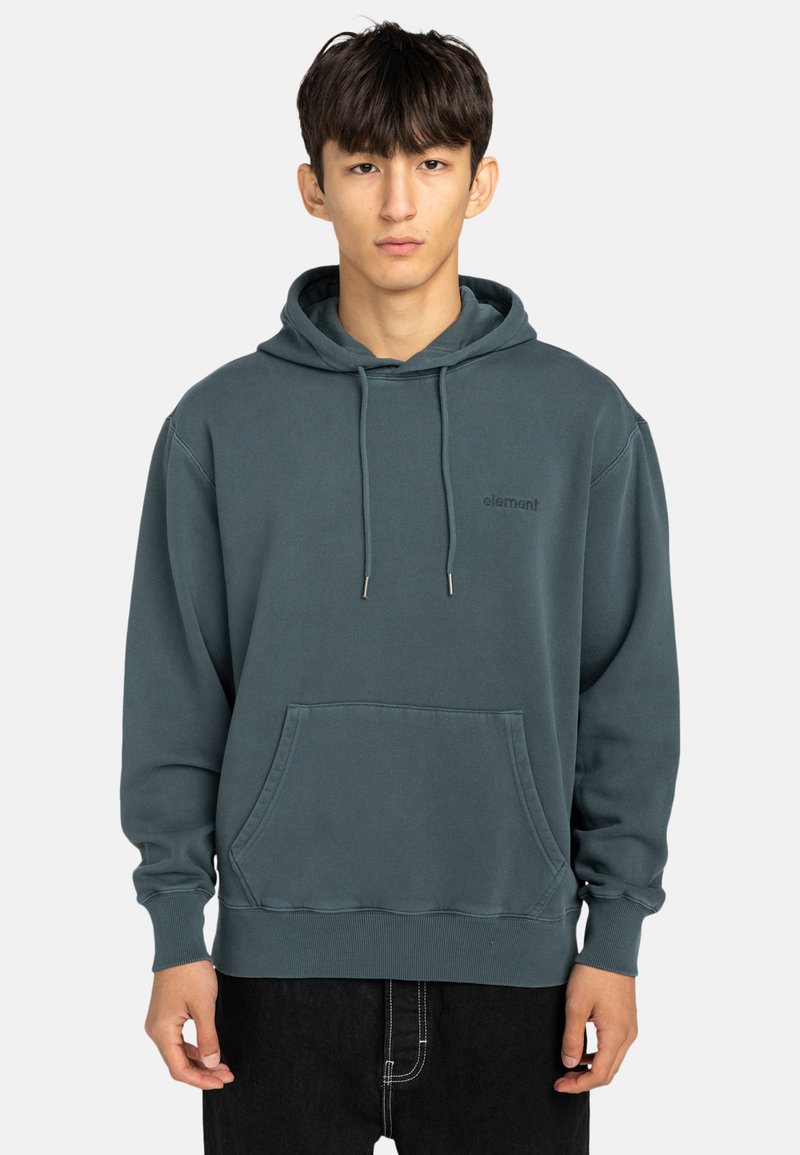 Hoodie i mörk teal, tillverkad av mjukt tyg. Har en framficka, ribbade ärmslut och diskret logo-brodyr på bröstet.