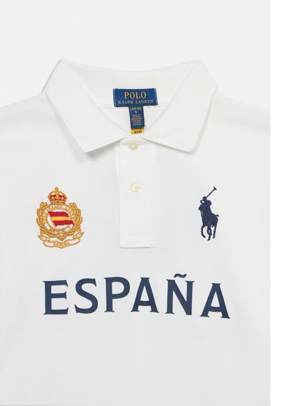 Λευκό πουκάμισο Polo Ralph Lauren με γιακά, κεντημένο ισπανικό αριστοκρατικό έμβλημα, λογότυπο παίκτη πόλο σε ναυτικό μπλε και κείμενο "ESPAÑA" σε ναυτικό μπλε.