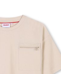 Beige katoenen t-shirt met een ronde hals, korte mouwen en een linker borstzak met een rits en een geperst logo detail.