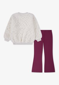 Svetlý krémový fleecový sveter s textúrovanými vzormi a rebrovanými manžetami, skombinovaný s nohavicami zloženými v slivkovej farbe s hladkým povrchom.