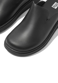 Black clogs made of smooth leather, featuring a rounded toe, slight heel, and an open top with a minimalist design.