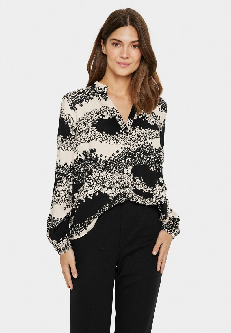 Blusa nera e crema con motivo floreale, maniche lunghe, chiusura a bottoni e vestibilità comoda. Tessuto liscio con una caduta morbida.