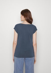 Camiseta de manga curta azul escura com um corte descontraído e decote em forma de coração, feita de um tecido suave, combinada com jeans de perna larga azul clara.