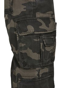 Pantalones cargo de camuflaje en tonos verde oscuro y gris, con múltiples bolsillos, tejido pesado y detalles de costura visibles.
