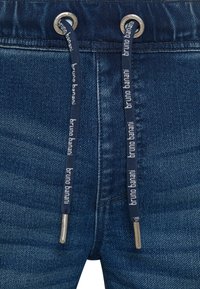 Denim joggers met een donkerblauwe tint, geribbelde textuur, zilveren oogjes en marineblauwe koorden met "bruno banani" branding.