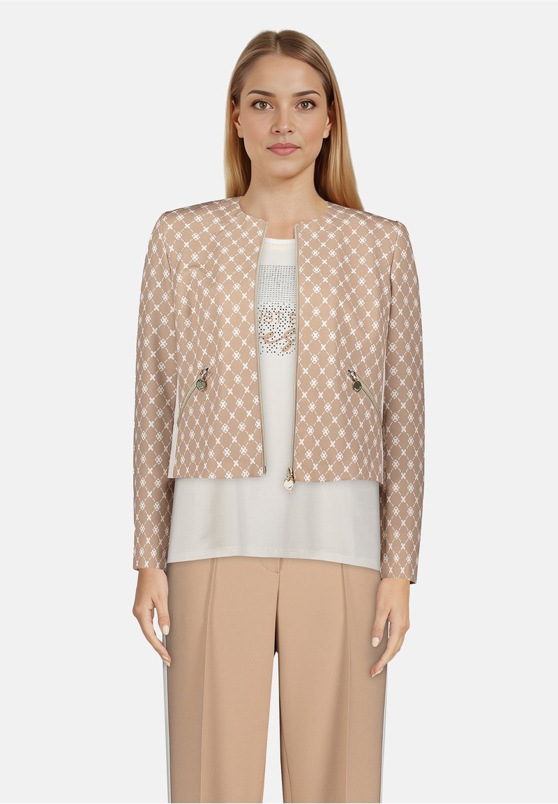 Veste courte beige avec motif en losange, ferrures dorées et deux poches avant, portée sur un haut clair et un pantalon beige.
