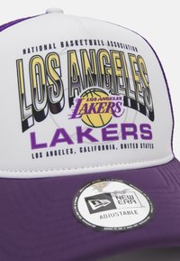 Los Angeles Lakers Cap mit weißer Vorderseite und lila Akzenten, grafischem Text und einem gebogenen lila Schirm. Inklusive New Era-Tag, verstellbare Passform.