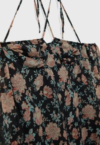 Robe noire avec motif floral rose et bleu clair, avec fines bretelles et détail plissé au niveau de la poitrine.