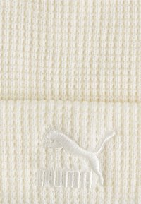 Berretto a maglia di colore avorio con texture a coste. Presenta un logo ricamato dello stesso colore sulla parte anteriore. Materiale morbido e caldo.