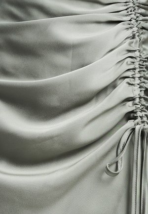 Hellgrauer Satin-Stoff mit seitlicher Raffung und Kordelzugdetails. Die glatte Textur hebt sanfte Drapierungen und geraffte Abschnitte hervor.