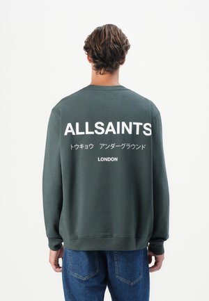 Tamnozeleni dukserica dugih rukava s bijelim otisnutim tekstom na leđima koji uključuje "ALLSAINTS" i "LONDON." Ležeran kroj.