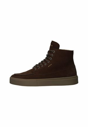 Zapatos de ante marrón de caña alta con punta redonda, ojales de metal y suela de goma. Marca visible en el lado. Presenta un acabado texturizado.