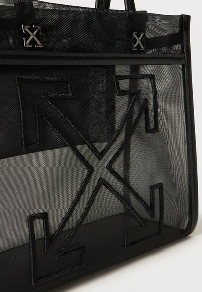 Μαύρη τσάντα ώμου από δίχτυ με μεγάλο κεντημένο σχέδιο σταυρού βελών και δύο μεταλλικές διακοσμήσεις σταυρού βελών κοντά στην επάνω άκρη.