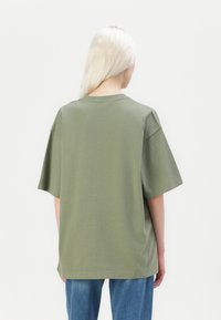 Overzichtelijk, kort-vinger t-shirt in olijfgroen katoen. Heeft een ronde halslijn en een losse pasvorm. Eenvoudig ontwerp zonder patronen of accenten.