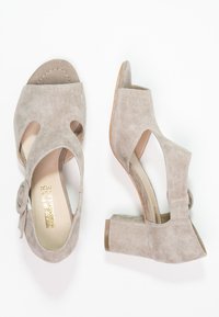 Sandali con tacco in suede grigio chiaro, con punta aperta, design con ritagli e un accent florale sul lato. Il tacco spesso offre stabilità.