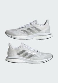 Weiße Sportschuhe mit strukturierter Mesh-Oberfläche, silbernem Drei-Streifen-Design, dämpfender Sohle und schwarzer Laufsohle für besseren Halt.