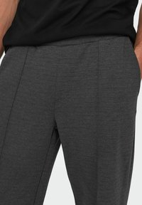 Grijze textuurbroek met een rechte snit, voorzien van een schone tailleband en zijzakken, gecombineerd met een zwart t-shirt.