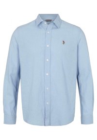 Camisa de manga larga azul claro hecha de lino, con cuello abotonado y botones en la parte delantera. Incluye un pequeño logo bordado en el pecho.