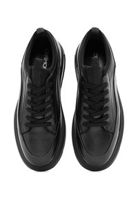 Un par de zapatillas negras de cuero con puntera redondeada, cordones negros y suelas de goma gruesa, mostradas desde arriba sobre un fondo blanco.