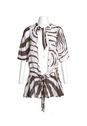 Blusa blanca con rayas de cebra marrones, mangas medias, lazo en el cuello y cinturilla con cordón, mostrada en un torso de maniquí blanco.